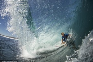 With blue waves tumbling over them, these surfers glide underneath