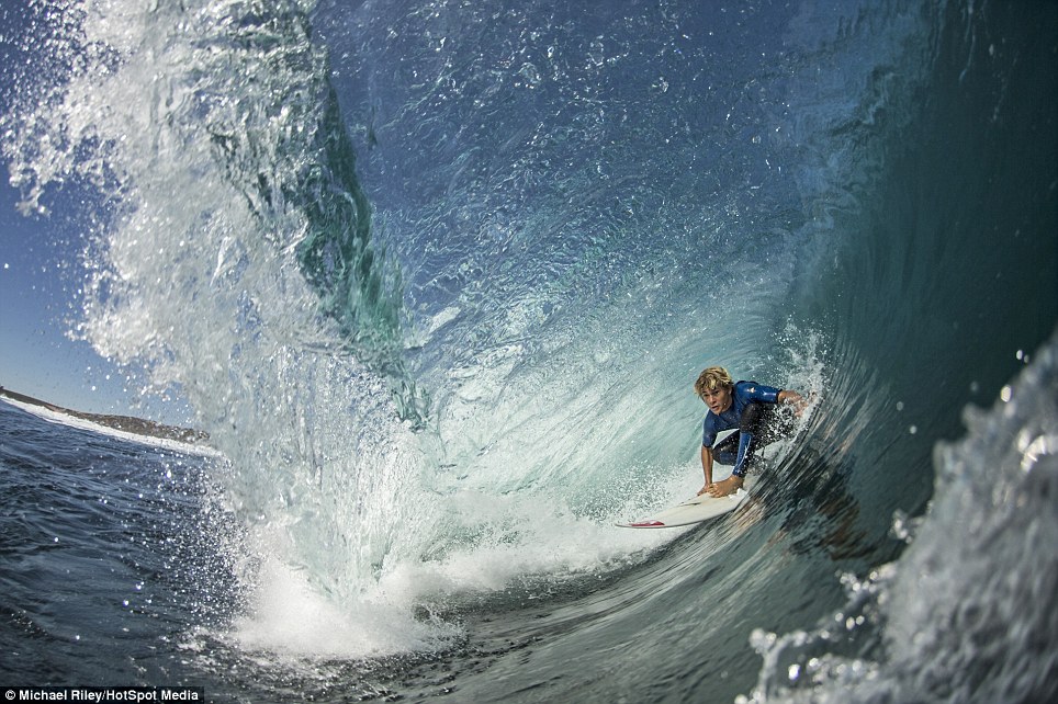 With blue waves tumbling over them, these surfers glide underneath