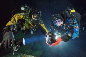 In a pitch black, 140-foot-deep underwater cave, three divers make