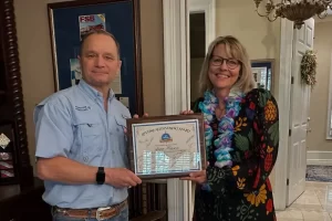Wayne Brown, CEO of Aggressor Adventures, presents Anne Hasson with